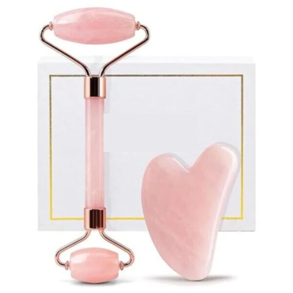 Top view of a rose quartz face massager and gua sha set on a soft fabric background