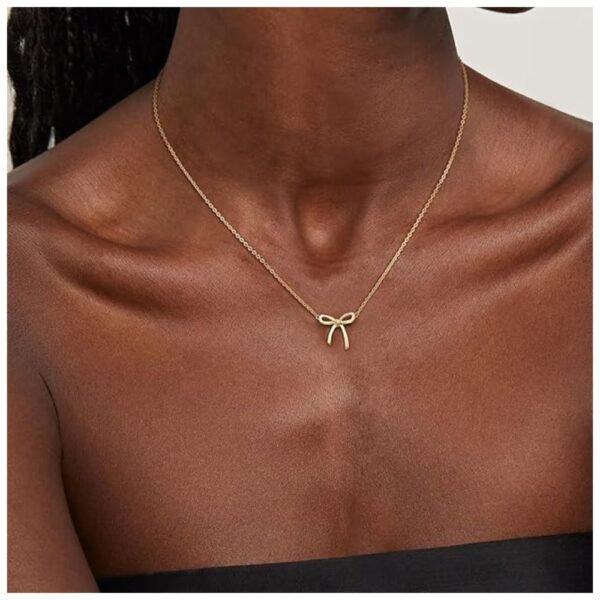 Woman wearing a dainty gold bow necklace, styled as a choker.