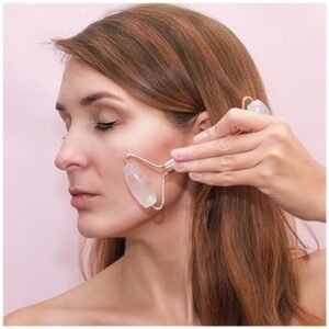 Smiling woman enjoying a spa moment while using a rose quartz face roller at home.