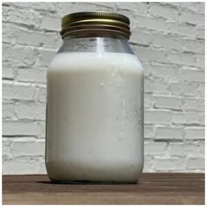 Glass bottle of whipped beef tallow moisturizer, showcasing its creamy texture and natural appearance.